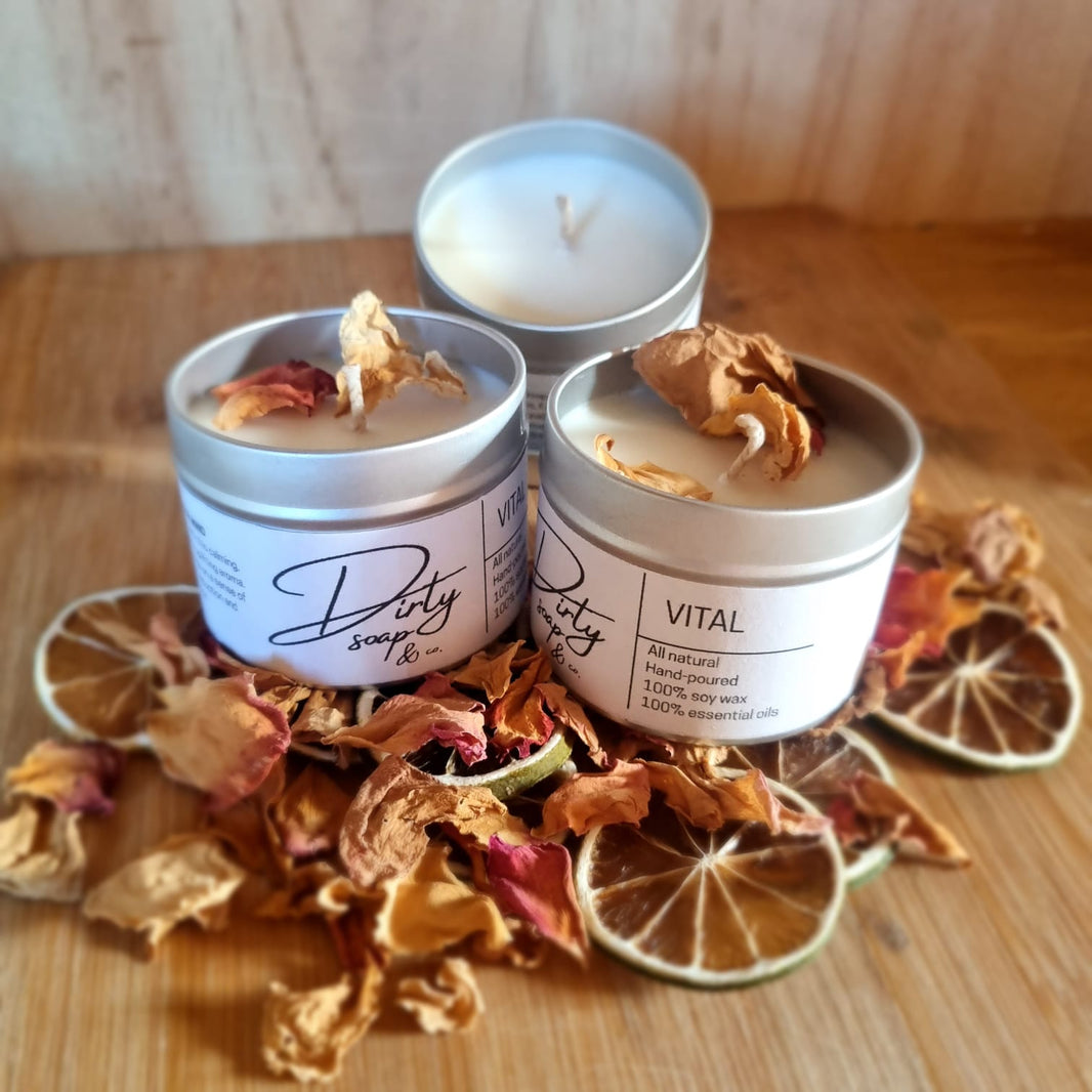 Three candles in metal containers with decorative elements on a wooden surface